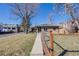 Charming brick home with a fenced yard, sidewalk, and mature trees on a sunny day at 2001 Grove St, Denver, CO 80211