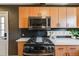 Contemporary kitchen with wood cabinets, a modern microwave, and a sleek black gas range at 2001 Grove St, Denver, CO 80211