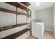 Bright laundry room featuring light wood floors, overhead light, open shelving, a window, washer, and hanging bar at 1905 S Linden Ct, Denver, CO 80224