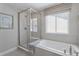 Bathroom showcasing a soaking tub with tiled surround, glass shower enclosure, and large window at 13334 Blue Amber Ct, Parker, CO 80134