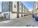 Row of townhouses featuring rear garages and ample parking space with trash and recycling bins at 1810 Irving St # 4, Denver, CO 80204