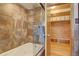 Bathtub shower with glass door, wood paneling, and storage in attached closet at 7890 W 43Rd Pl, Wheat Ridge, CO 80033