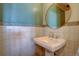 Bathroom featuring pedestal sink, tiled walls, and a round mirror at 7890 W 43Rd Pl, Wheat Ridge, CO 80033