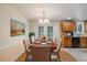 Dining room with a view of kitchen featuring modern light fixtures, wooden floors, and seating for six at 8137 Vanguard Dr, Denver, CO 80221