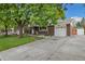 Spacious driveway leading to a two-car garage complements this brick home with mature trees at 8137 Vanguard Dr, Denver, CO 80221