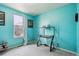 Bright bedroom space with turquoise painted walls, large window and a modern desk at 714 S Tabor St, Elizabeth, CO 80107