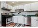 Functional kitchen features white cabinetry, stainless steel appliances and a black and white checkerboard rug at 714 S Tabor St, Elizabeth, CO 80107