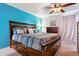 This primary bedroom features a wood frame bed with built-in drawers, ceiling fan, and a calming blue accent wall at 714 S Tabor St, Elizabeth, CO 80107