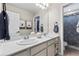 Bright bathroom featuring double sinks, white cabinets, a large mirror, and separate toilet/shower room at 502 Green Mountain Dr, Erie, CO 80516