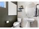 Stylish powder room with pedestal sink, round mirror, modern floating shelves, and dark accent wall at 502 Green Mountain Dr, Erie, CO 80516