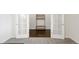 Transitional space with bright white walls and doors leads to an office with French doors and gray carpeting at 12563 Grape St, Thornton, CO 80241