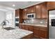 Elegant kitchen featuring granite countertops, stainless steel appliances, and dark wood cabinetry at 12563 Grape St, Thornton, CO 80241