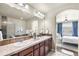 Bathroom featuring a tiled shower, a soaking tub, dual sinks, and modern lighting with a view to the bedroom at 10067 Bluffmont Ct, Lone Tree, CO 80124
