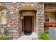 Inviting entryway features a stylish front door framed by a stone archway and a decorative lantern at 10067 Bluffmont Ct, Lone Tree, CO 80124