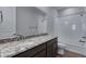 Well-lit bathroom features a granite countertop, a large mirror, and a shower over the tub at 13531 E 99Th Pl, Commerce City, CO 80022
