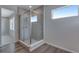 Walk in shower features glass enclosure, showerhead, tiled walls, and luxury wood flooring at 13531 E 99Th Pl, Commerce City, CO 80022