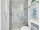 Modern tiled shower featuring glass door and shower head, next to the vanity at 1007 Chase St, Lakewood, CO 80214