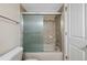 A bathroom featuring a tub and shower with a glass sliding door and neutral toned tile surround at 4681 S Decatur St # 227, Englewood, CO 80110