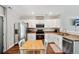 Bright kitchen featuring white cabinets, stainless steel appliances, and a cozy eat-in area with wood-look flooring at 6142 Gorham St, Frederick, CO 80530