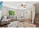 Bright living room with a cozy sectional sofa, ceiling fan, staircase access, and a view into the bathroom at 6142 Gorham St, Frederick, CO 80530