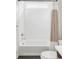 Bathroom with white tiled shower-tub combination and neutral striped shower curtain at 6251 N Galena St, Denver, CO 80238