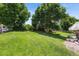 Expansive backyard features a lush green lawn, mature trees, and a patio with decorative umbrellas and furniture at 17298 E Lake Pl, Aurora, CO 80016