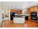 Spacious kitchen with wood cabinets, black appliances, granite countertops, and a central island for meal preparation at 17298 E Lake Pl, Aurora, CO 80016