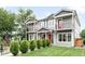 Inviting two-story townhouse showcases gray siding, red doors, charming balconies, and lush, landscaped front yard at 4730 S Acoma St, Englewood, CO 80110