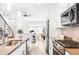 Open kitchen with white cabinets, stainless steel appliances, an island with seating, and views of the dining and living areas at 4730 S Acoma St, Englewood, CO 80110