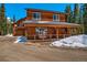 Wooden home with a covered porch and balcony set against a backdrop of tall evergreen trees at 532 Kimmes Ln, Breckenridge, CO 80424