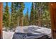 Outdoor hot tub with a snow-covered cover amidst tall evergreen trees in a scenic setting at 532 Kimmes Ln, Breckenridge, CO 80424