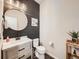 Charming powder room with wood accent wall, modern vanity, round mirror, and stylish fixtures at 42729 Ivydel Cir, Elizabeth, CO 80107