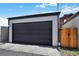 A detached gray garage features a secure dark garage door and a wooden fence, offering privacy and convenience at 3711 Mariposa St, Denver, CO 80211