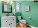 Charming bathroom with bright green walls, modern vanity, and a framed mirror at 8544 S Upham Way, Littleton, CO 80128