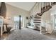 Bright living room featuring a spiral staircase, balcony access with mountain views, and neutral decor at 10872 W Evans Ave # 3D, Lakewood, CO 80227