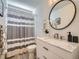 Bright bathroom featuring a white vanity with marble countertop, round mirror, and shower with a gray striped curtain at 12653 Jersey E Cir, Thornton, CO 80602