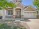 Charming front entrance with stone accents, covered porch, and access to a spacious two car garage at 12653 Jersey E Cir, Thornton, CO 80602
