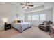Primary bedroom features a tray ceiling, ceiling fan, large windows, and a comfy armchair at 87 Green Fee Cir, Castle Pines, CO 80108