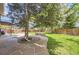 Beautiful backyard featuring a well-manicured lawn, mature trees, stone patio, and privacy fence at 6338 S Oneida Ct, Centennial, CO 80111