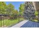 Balcony view with black metal railing overlooking a green backyard with mature trees and privacy fencing at 6338 S Oneida Ct, Centennial, CO 80111