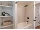 Modern shower and tub area with vertical tile and sleek black fixtures with added shelving at 2598 Teller St, Lakewood, CO 80214