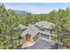 Aerial view of a gray house with a stone entryway, a gray roof, and lots of surrounding trees at 29433 Firethorne Ct, Evergreen, CO 80439
