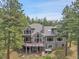Rear exterior view showing the upper and lower decks, hot tub, and mountain landscape beyond the treeline at 29433 Firethorne Ct, Evergreen, CO 80439