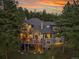 Exterior view displaying tiered wood decks, a hot tub, and large windows overlooking lush greenery at 29433 Firethorne Ct, Evergreen, CO 80439