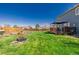 This home includes a spacious backyard with a fire pit, lush lawn, a deck area, and privacy fence at 4465 E 121St Pl, Thornton, CO 80241