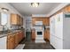 Functional kitchen featuring wood cabinets, granite countertops, and modern white appliances at 4465 E 121St Pl, Thornton, CO 80241