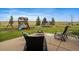 Backyard patio features a fire pit and play structure surrounded by manicured lawn and mature trees at 5861 E Valley Hi Dr, Parker, CO 80138