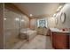 Elegant bathroom with glass shower, soaking tub, double vanity, and stained-glass window at 5861 E Valley Hi Dr, Parker, CO 80138