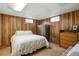 Basement bedroom with wood paneling, a white bed with patterned bedding, and a closet at 7472 Jay Ct, Arvada, CO 80003
