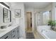 Bathroom with double sinks, soaking tub, glass shower, and a stylish black and white accent rug at 4270 Defoe St, Strasburg, CO 80136